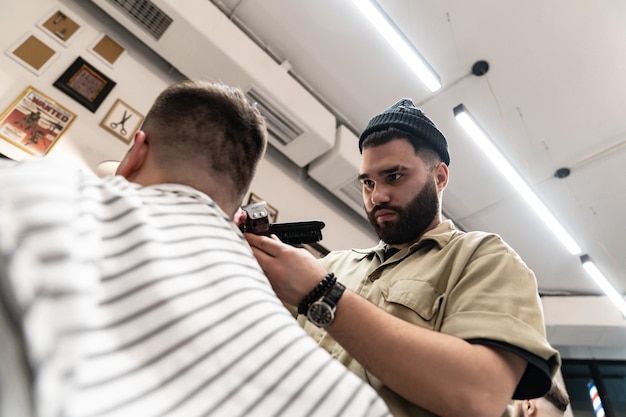 The client receives a haircut and hair styling in a beauty salon. Barber serves the client.